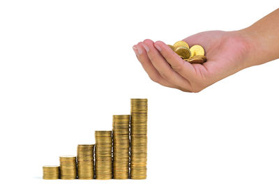 Cropped image of hand holding coin stack against white background