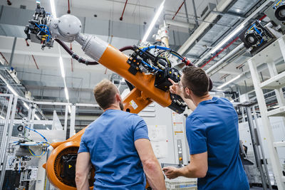 Two technicians examining industrial robot in a factory