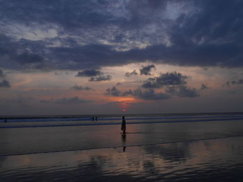 Silhouette person standing on beach against sky during sunset