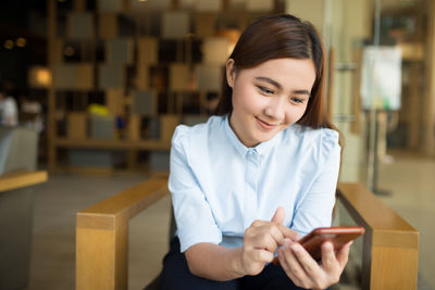 Portrait of a smiling young woman using mobile phone
