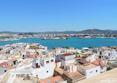 High angle view of buildings in city against clear blue sky