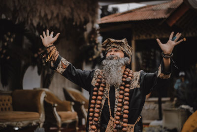 Man wearing traditional clothing gesturing while standing outdoors