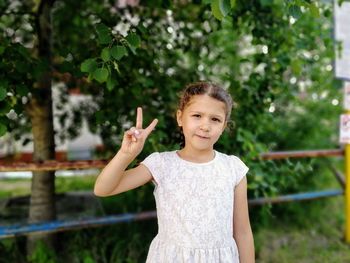 Portrait of girl standing against trees