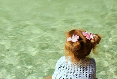 Rear view of girl sitting by water
