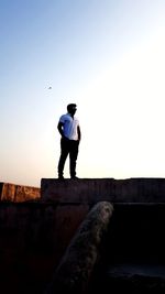 Rear view of man standing against clear sky