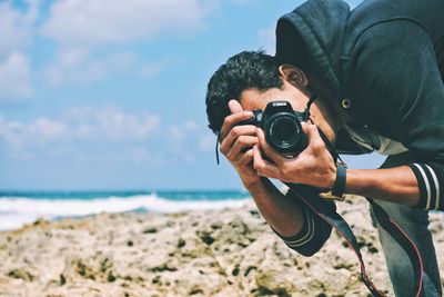 Close-up of man photographing camera on beach