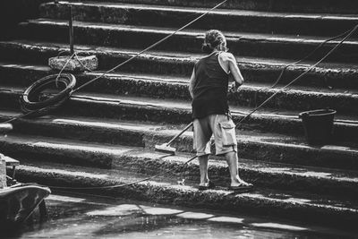 Rear view of man cleaning steps