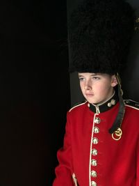 Thoughtful boy wearing uniform against black background