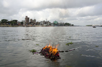 Scenic view of river by buildings against sky