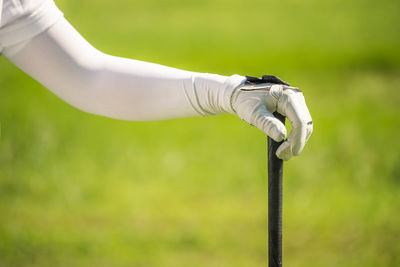 Cropped hand of golfer with golf club at course