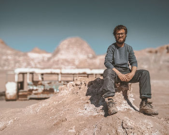 Portrait of man standing on rock against mountain