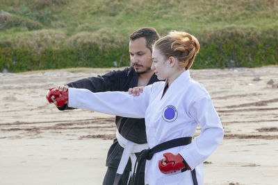 Coach teaching karate to teenage girl at bach