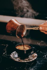 Close-up of hand pouring tea in cup