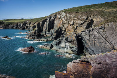 Rock formations by sea against clear sky