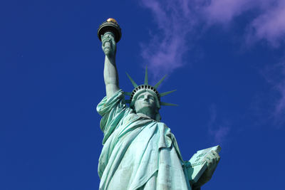 Low angle view of  lady liberty statue against blue sky