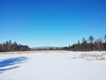 Snow covered landscape against clear blue sky