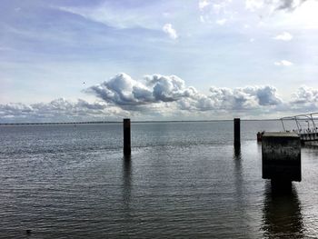 Wooden posts in sea against sky