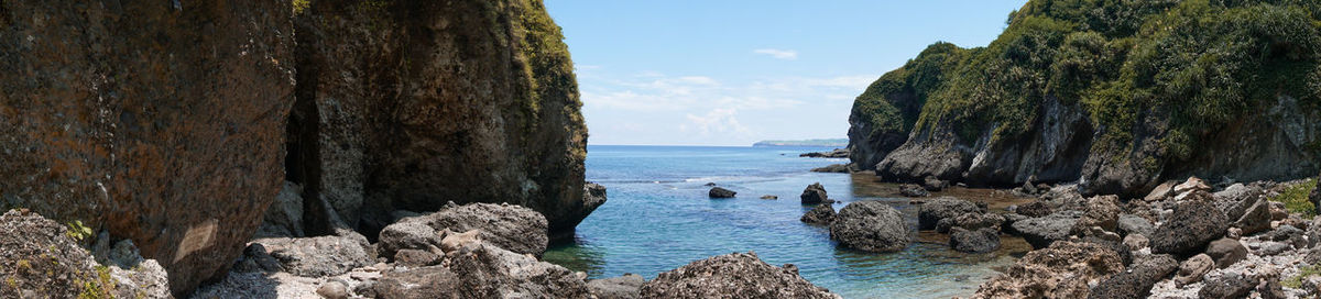 Panoramic shot of rocks by sea against sky