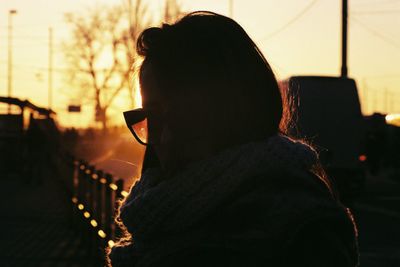 Close-up of silhouette woman wearing sunglasses during sunset