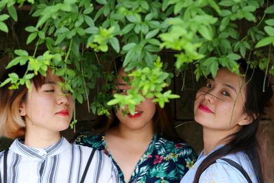 Portrait of woman with friends standing below branches