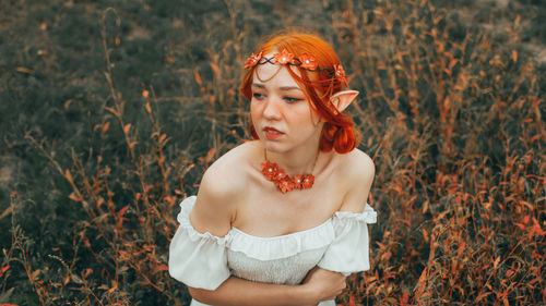 Portrait of young woman standing against plants