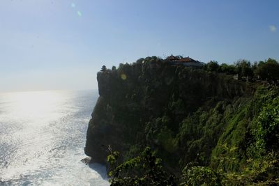 Scenic view of cliff by sea against clear sky