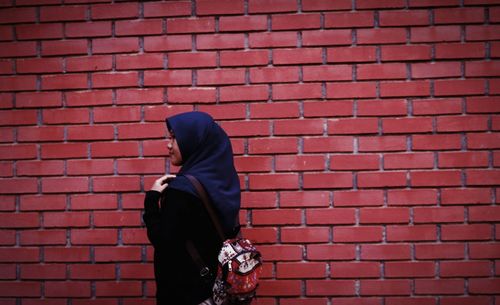 Woman standing against brick wall