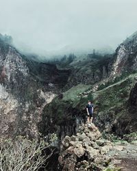 People on rocks against mountains