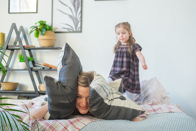 Frustrated mother covering eyes with pillow lying on bed