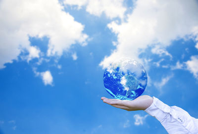 Low angle view of person hand against blue sky