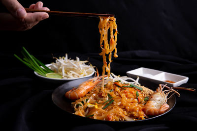 Close-up of hand holding noodles in bowl