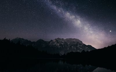 Scenic view of lake and mountains against sky at night