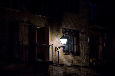 Illuminated street light by building at night