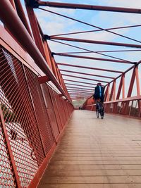 Rear view of man walking on footbridge