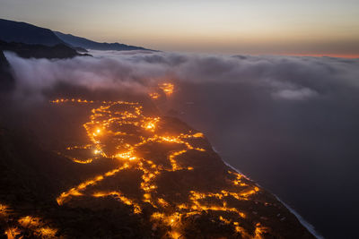 Aerial view of illuminated mountains against sky