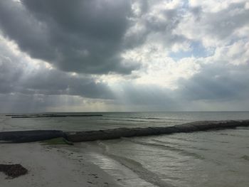 Scenic view of beach against cloudy sky