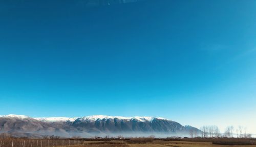 Scenic view of snowcapped mountains against clear blue sky