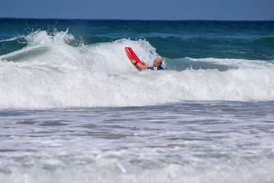 Scenic view of sea waves rushing towards shore with a surfer 