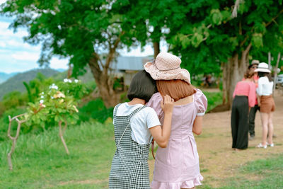 Rear view of friends walking against plants