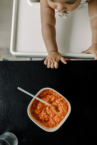 Directly above shot of baby boy by food bowl at home