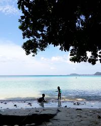 People standing on beach against sky