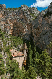 House amidst trees and buildings against mountains