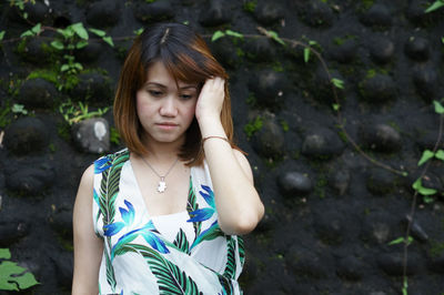 Young woman looking down against wall