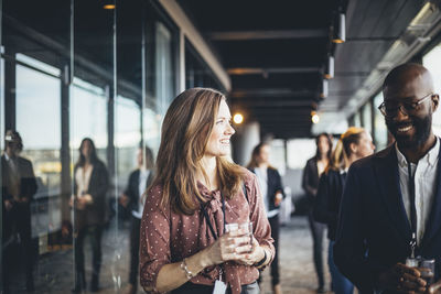 Smiling businesswoman talking to coworker in office corridor