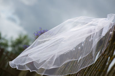 Veil on wooden fence against cloudy sky