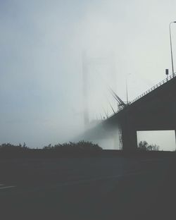 Low angle view of suspension bridge in foggy weather