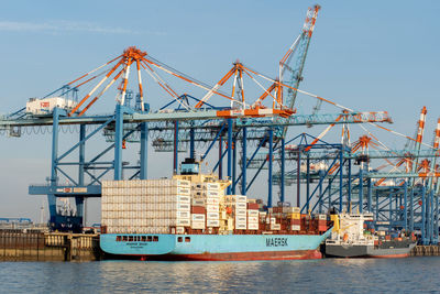 Cranes at commercial dock against sky