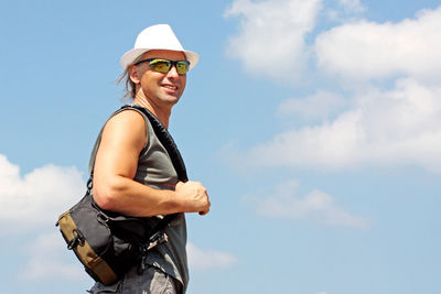 Low angle view of man wearing sunglasses standing against sky