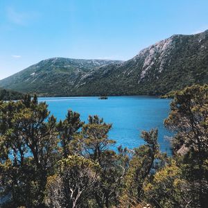 Scenic view of lake and mountains against clear blue sky