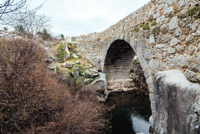 Arch bridge over river against sky